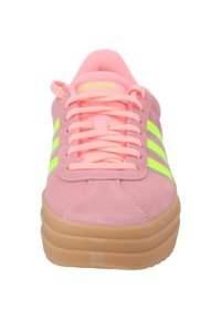 Różowe zamszowe sneakersy z neonowymi zielonymi paskami, okrągłym noskiem i pasującymi sznurowadłami. Posiadają grubą, jasnobrązową gumową podeszwę, która dodaje wysokości.