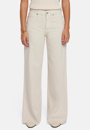 Pantaloni larghi di colore crema realizzati in tessuto leggero. Presentano una vita alta con chiusura a bottone e cerniera, tasche laterali e cuciture a vista.