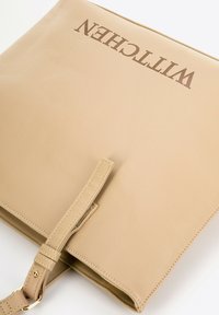Beżowa skórzana torba tote o teksturowanym wykończeniu. Posiada brązowe wytłoczone logo oraz odpinany pasek z złotymi akcentami.