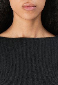 Black ribbed knit top with a square neckline, featuring a textured surface and slightly fitted design, suitable for casual wear.