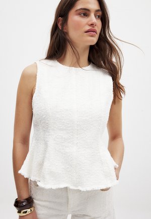 White sleeveless top with textured fabric, flared peplum hem, and a round neckline. Features visible side seams and frayed edges.