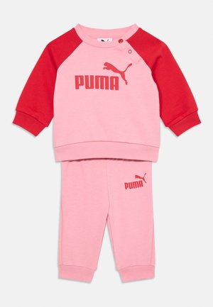 Roze i crveni dukserica s dugim rukavima i logom. Uparene roze hlače s logom. Mekana tkanina, raglan dizajn i detalj s kopčom.