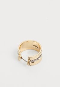 Gulltone ring med en glatt ring med en rad av klare krystaller og et unikt sommerfugl-låsdesign. Innvendig merket med "DKNY."