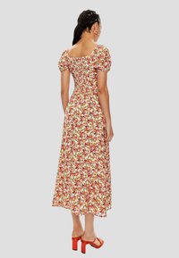 Vestido midi floral con mangas abullonadas y trasero fruncido. Presenta una vibrante mezcla de flores rojas, naranjas y amarillas sobre un fondo blanco.