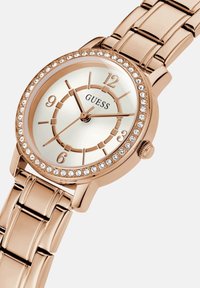 Roosakuldne kell, millel on ümmargune kellaface, valge dial, kristallaktsendid ja polesitud käekett. Omab tunniindikaatoreid ja kahte näppu.