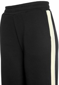 Schwarze Jogginghose mit elastischem Bund, ausgestattet mit einem seitlichen weißen Streifen. Der Stoff wirkt weich mit einer glatten Textur.