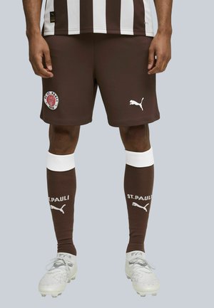 Rudos futbolo šortai su baltais raštais, su "FC St. Pauli" logotipu. Balta "Puma" logotipas ant šortų ir tamsiai rudi kojinaitės su baltais akcentais.