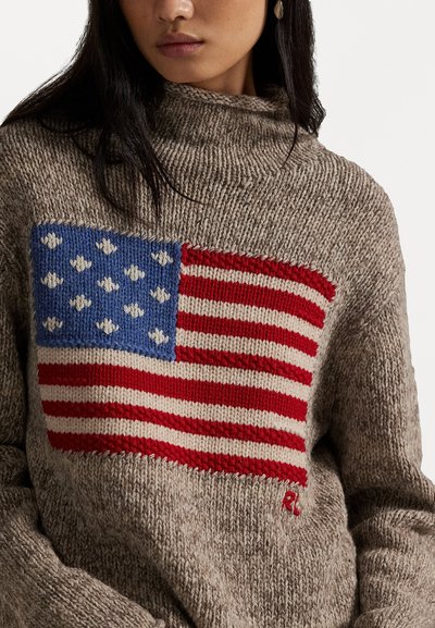 Pletený sveter v svetlohnedej farbe s veľkým dizajnom americkej vlajky v modrej, červenej a bielej farbe. Obsahuje rolákový golier a textúrovanú látku.