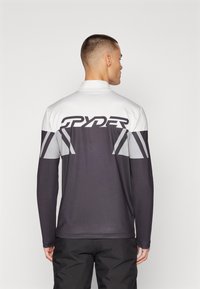 Sportieve longsleeve shirt met een gesplitst kleurontwerp in wit, grijs en donkergrijs. Grote "SPYDER" logo op de achterkant. Gladde stofstructuur.
