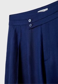 Jupe bleu marine avec fermeture à deux boutons à la taille, devant plissé et poches latérales, réalisée en tissu texturé.