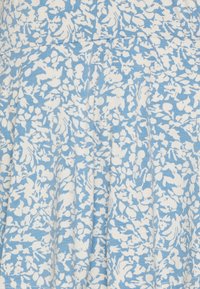 Látka s květinovým vzorem v světle modré a bílé barvě s jemnou texturou. Design obsahuje sklady a pohodlné přizpůsobení.