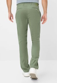 Pantaloni verde in cotone misto a vestibilità slim, dotati di due tasche posteriori, passanti per cintura e una texture liscia. Abbinati a sneakers bianche.