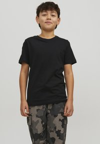 T-shirt in cotone nero con maniche corte, collo rotondo, indossato da un bambino; abbinato a pantaloni cargo a fantasia mimetica grigia con tasche.