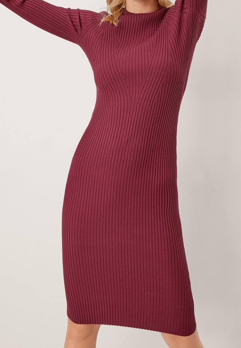 Abito rigato color bordeaux con silhouette aderente, scollo a barca e maniche lunghe, caratterizzato da strisce verticali per un tocco di texture in più.