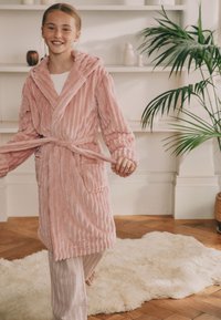 Roosa sametine hommikumantel tekstuurse triibulise mustriga, kapuutsiga ja vöökandiga. Omab täispikki varrukaid ja küljetaskut, kantud triibuliste pükstega.