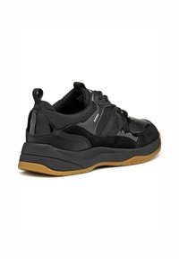 Zapatilla deportiva negra con parte superior de ante texturizado y sintético, acentos brillantes en contraste, suela de goma y tirador trasero para facilitar su uso.