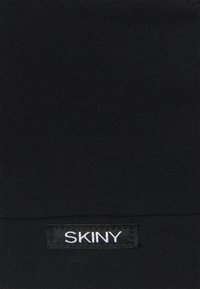 Tissu noir avec une texture lisse et côtelée, présentant une étiquette blanche "SKINY" cousue sur le bord inférieur. Design simple et minimaliste.