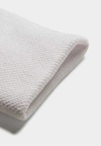 Tela blanca texturizada, suave y tejida, con un borde doblado. Un pequeño patrón visible crea un sutil detalle en la superficie.