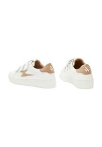 Baskets blanches en cuir et daim, avec un design en forme d'éclair, une semelle en caoutchouc blanc texturé et un accent de talon tan.