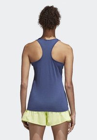 Mörkblå ärmlös linne med racerback-design och slät textur, tillsammans med ljusgröna volangshorts.