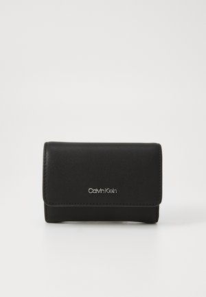 Black leather wallet with a fold-over design, featuring silver Calvin Klein logo and clean stitching details. Compact shape with smooth texture.