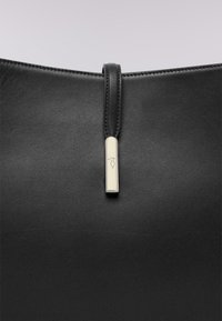 Czarna skórzana torba o gładkiej fakturze, z akcentami ze srebrnego metalu oraz paskiem z zamknięciem u góry z metalową etykietą z logo.