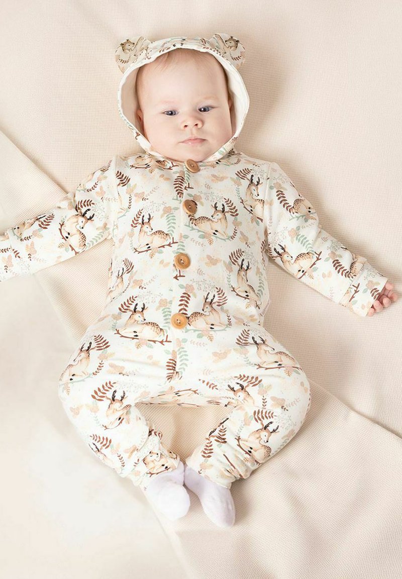 Kremowy kombinezon z kapturem z uszkami niedźwiedzia, drewnianymi guzikami oraz nadrukami nawiązującymi do przyrody, w tym sarną i liśćmi. Miękki, elastyczny materiał.