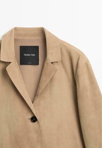 Veste en daim beige avec col à revers cranté et un seul bouton noir, étiquetée Massimo Dutti, fabriquée en Inde.