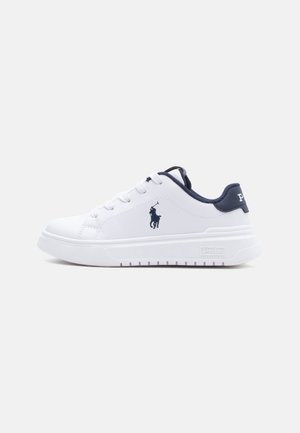 Baskets basses blanches avec doublure intérieure bleu marine, lacets, et logo Polo sur le côté et le talon. Semelle épaisse blanche avec dessous texturé.