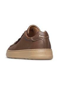 Sneaker in pelle marrone con suola in gomma beige, forma arrotondata, cuciture sottili e logo impresso sul tallone. Texture liscia in tutto il prodotto.