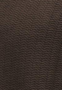 Tissu tricoté brun foncé avec un motif en zigzag subtil créant une apparence texturée et tissée.