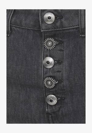 Primo piano di tessuto in denim scuro che mostra quattro bottoni metallici decorativi con disegni circolari alternati lisci e perlati.