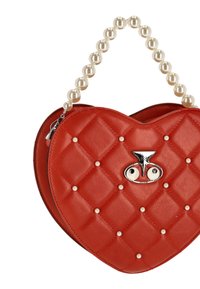 Sac à main rouge en forme de cœur avec texture matelassée, poignée en perles et ferrures argentées ornées de motifs d'œil et de clous décoratifs.