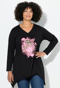 Haut noir à manches longues avec un col en V et un imprimé graphique de tigre rose. Présente un ourlet asymétrique et un tissu doux.
