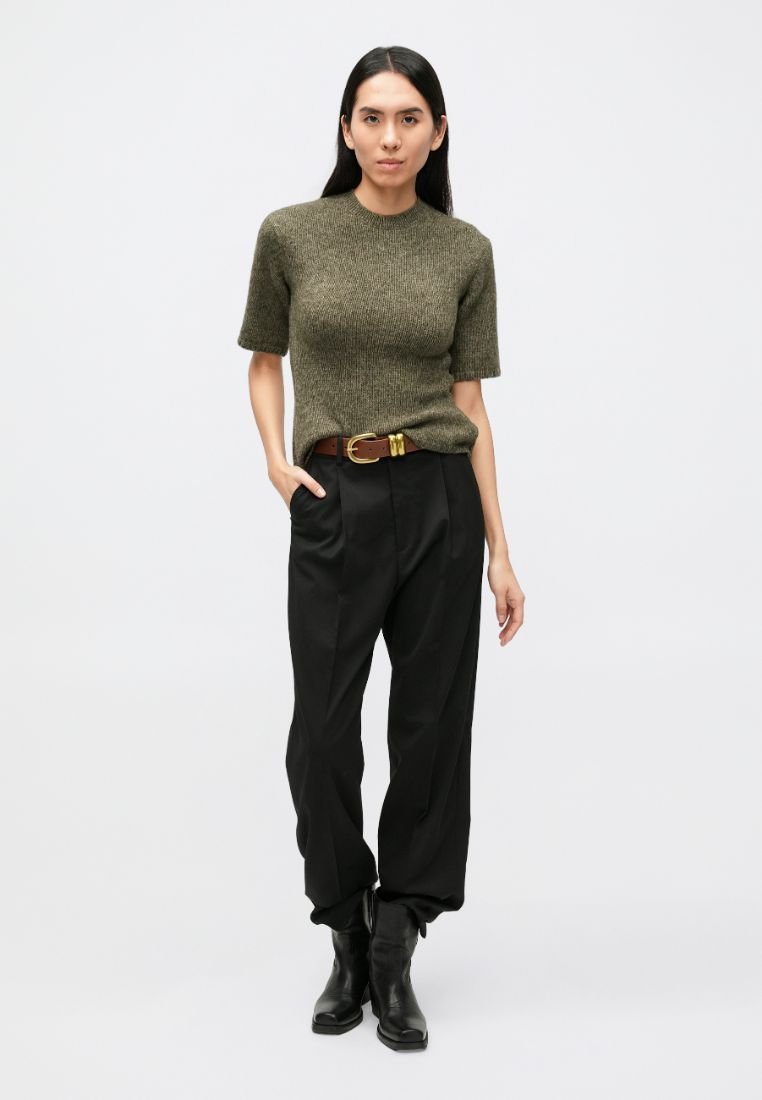 Pull en maille vert olive à manches courtes, associé à un pantalon noir taille haute et une ceinture marron. Des bottines noires complètent le look.
