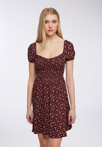 Abito floreale color bordeaux con maniche a palloncino corte, scollatura quadrata e corpetto aderente. Il materiale ha una consistenza morbida con una gonna fluida.