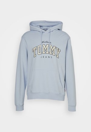 Lyseblå hættetrøje med frontlomme og snore, "Worldwide TOMMY JEANS" tekst trykt på brystet i hvide og sorte bogstaver.