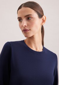Maglione blu navy realizzato in un tessuto a maglia testurizzato, con scollatura a girocollo e maniche lunghe. Design semplice e classico senza decorazioni.