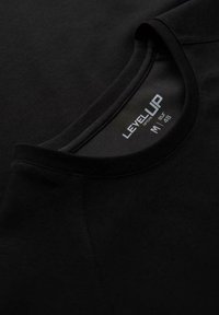 Sort crew neck t-shirt med en glat tekstur, der har et label med teksten "LEVEL UP", størrelse M (EU 48) i hvid skrift på indersiden af kraven.