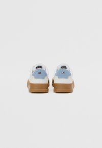 Zapatillas blancas con acentos azul claro, suelas de goma y costuras en tono. Presenta un detalle de logo en el talón y un cuello acolchado.