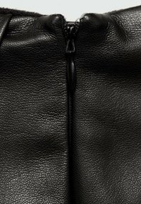 Black leather bag featuring a prominent zipper at the top, with a textured surface and subtle grain pattern.