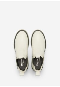 Zapatillas blancas sin cordones con parte superior de cuero suave, puntera redondeada, suelas negras y acentos en contraste. Presentan una lengüeta para facilitar su uso.