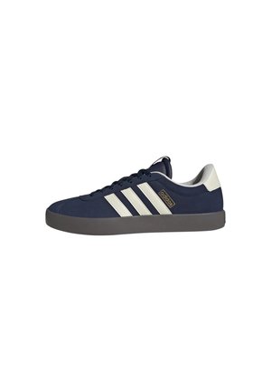 Baskets Adidas bleu marine avec bandes blanches, semelle grise et languette blanche au talon, vues de profil sur fond blanc.