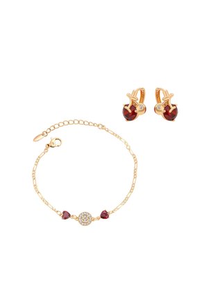 Pulsera de oro con piedras rojas en forma de corazón y un colgante circular, combinada con pendientes de oro con piedras redondas rojas y pequeños cristales transparentes.