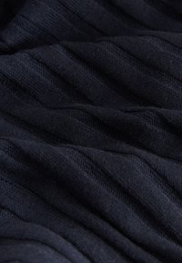 Granatowa dzianina prążkowana o miękkiej fakturze, z wypukłymi paskami i gładkim wykończeniem. Brak widocznych elementów metalowych ani ozdobników.