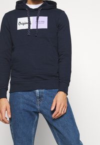 Marinblå hoodie i bomullsblandning med framficka, kontrasterande logotypmärken och huva med dragsko och texturerade snören.