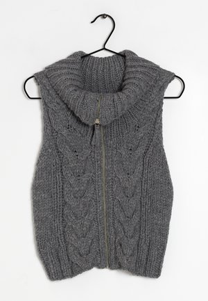 Szara dzianinowa kamizelka bez rękawów z wysokim, podwiniętym kołnierzem i przednim zamkiem błyskawicznym, wisząca na czarnym wieszaku na białym tle.