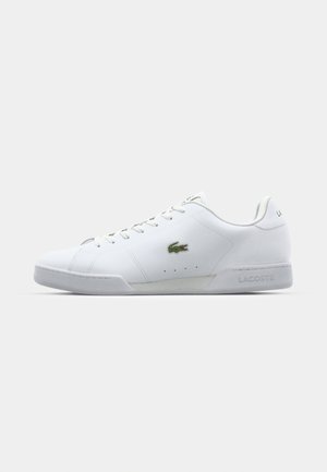 Valkoiset nahkaiset tennarit matalalla varrella, joissa on vihreä Lacoste-logo, tekstuuripinnat ja litteä kumipohja. Sisältää klassisen nauhakiinnityksen.