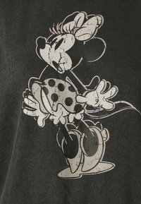 Camiseta negra con un gráfico de estilo vintage de una chica con un vestido de lunares, contorneada en blanco y rosa, sobre el tejido.
