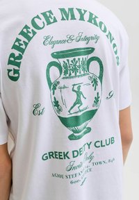 Λευκή μπλούζα με πράσινο τύπωμα ελληνικής αμφορέως, αρχαίου πολεμιστή και κείμενο που αναφέρεται στην Ελλάδα, Μύκονο, Greek Deity Club και Elegance & Integrity.